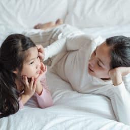 Mother talking with her daughter in bed.