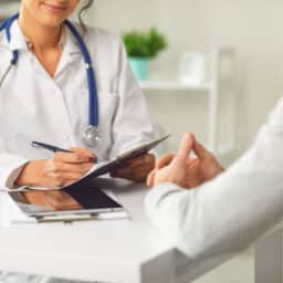 Doctor speaking with a patient in doctor's office setting.