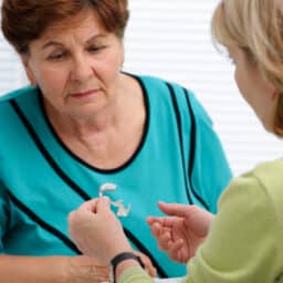 Audiologist showing a hearing aid to a female patient.