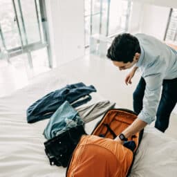 Man wearing a hearing aid packing a suitcase.