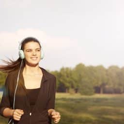 Woman with headphones jogging outside.