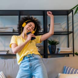 Woman listening to music dancing on her couch