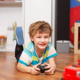 A boy playing with radio-controlled car at home.