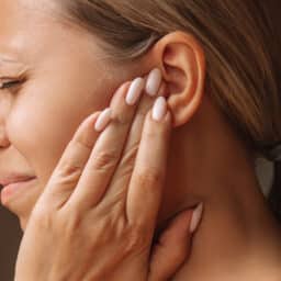 Woman with an earwax blockage holding her ear