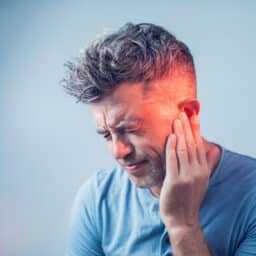 Man with tinnitus holds ear