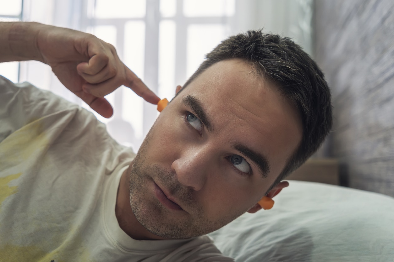 Man wearing earplugs to block out noise.