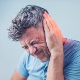 Man with tinnitus holding his left ear.