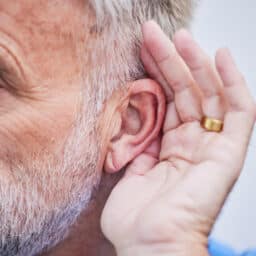 Man holds hand behind ear to hear