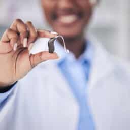 Audiologist holding up a behind-the-ear hearing aid