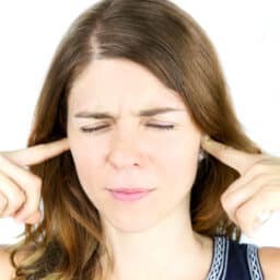 Woman holds fingers over ears
