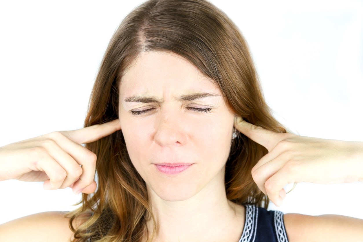 Woman holds fingers over ears