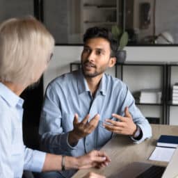 Two coworkers talking at a desk
