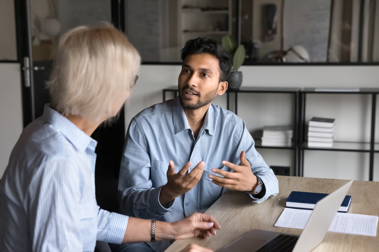 Two coworkers talking at a desk.