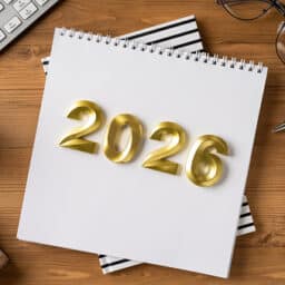 A desk scene for year end and holiday plans with a 2026 calendar, gift, coffee, and office items suggesting Christmas and New Year greetings